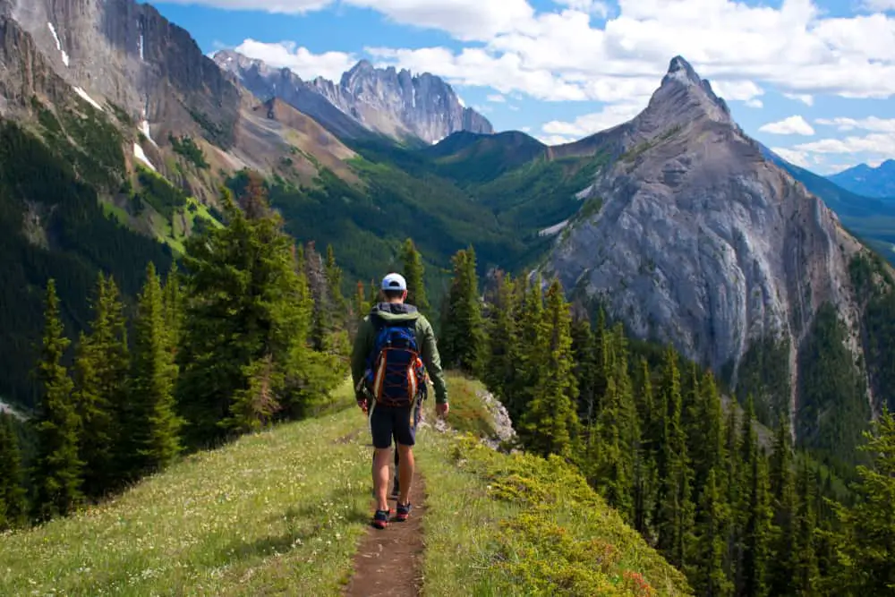 THis is a man hiking through the Canadian Rockies with the mountain in the background.