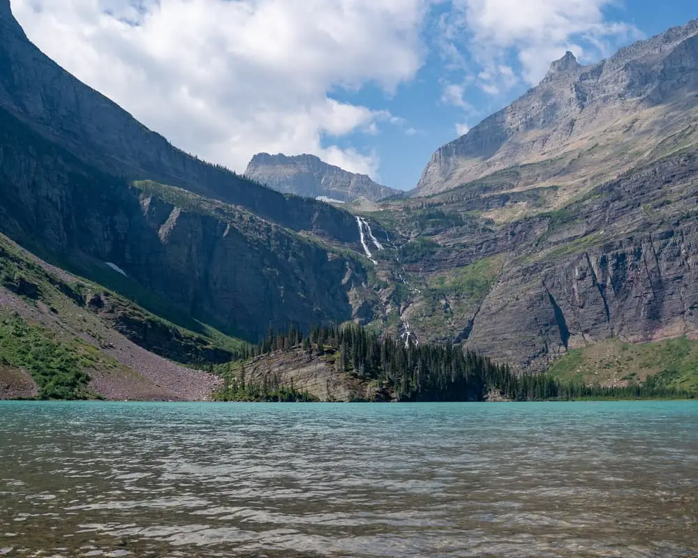 This is a far off view of the Glacier National Park landscape with mountains and forests.