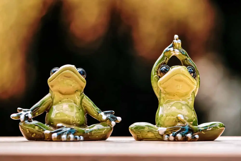 These are a couple of ceramic frog figurines doing yoga positions.