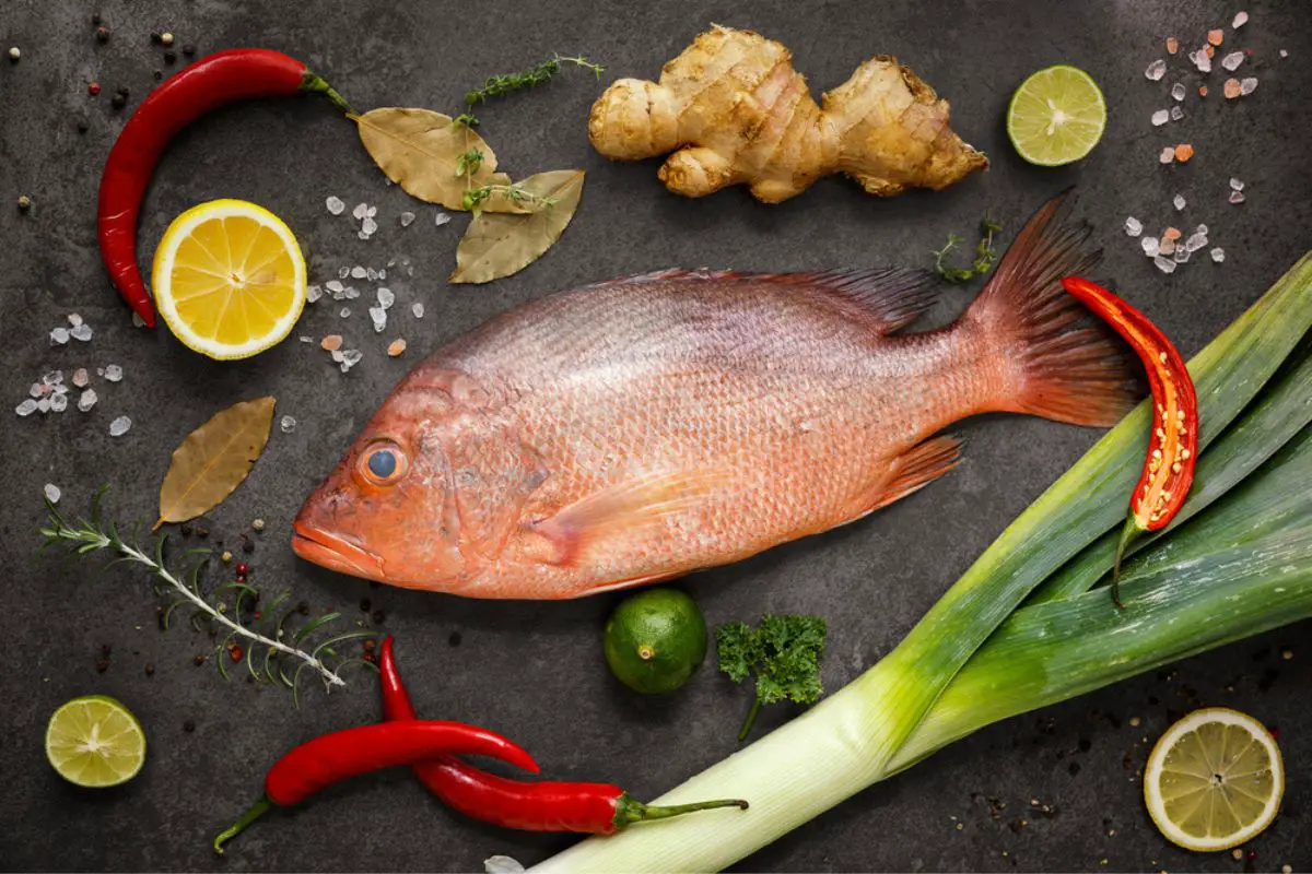 Fresh ingredients to cook fish, red snapper, leak, lime, lemon, parsley, chili pepper and ginger.